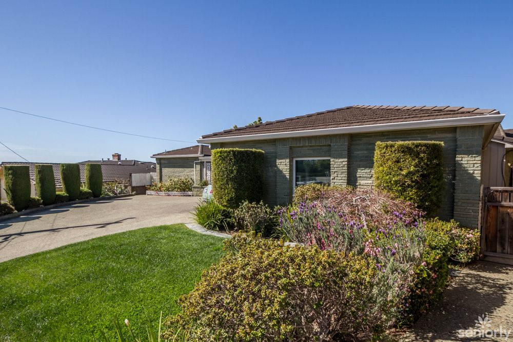 A suburban house with well-maintained landscaping and a clear sky.
