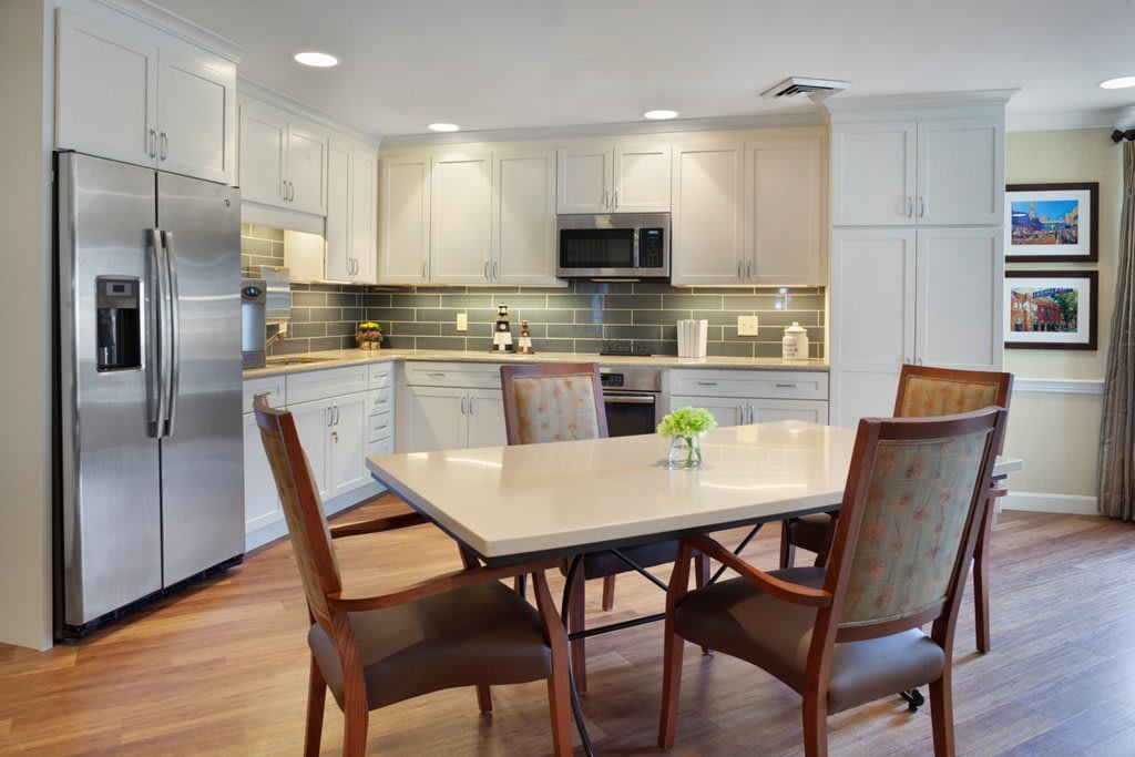 A modern kitchen with a dining area featuring a table and chairs, stainless steel appliances, and stylish cabinetry.