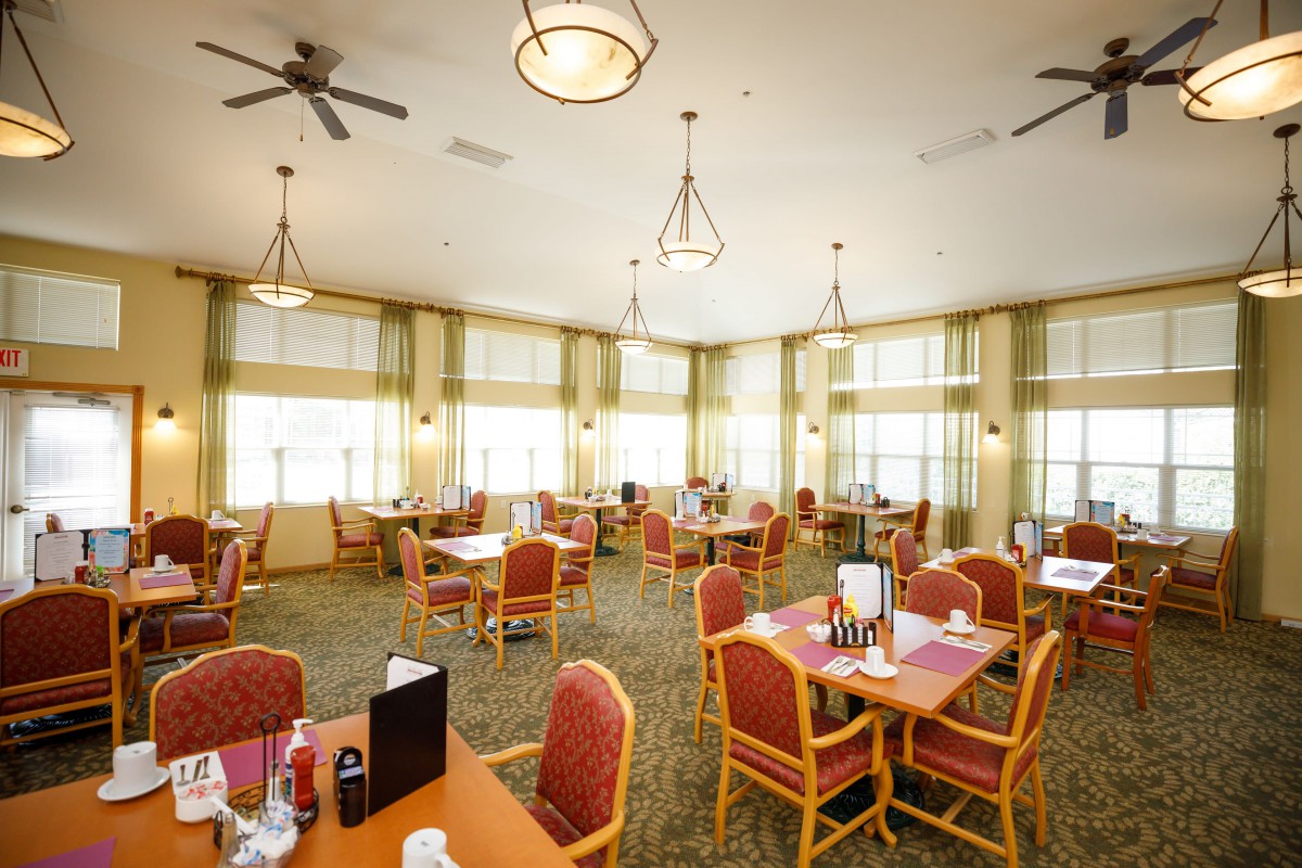 A well-lit dining area with neatly arranged tables and chairs.