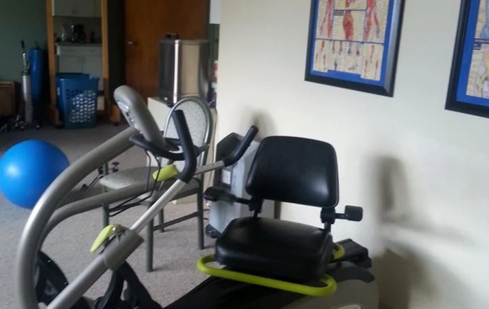A gym room featuring exercise equipment and a poster of human anatomy on the wall.