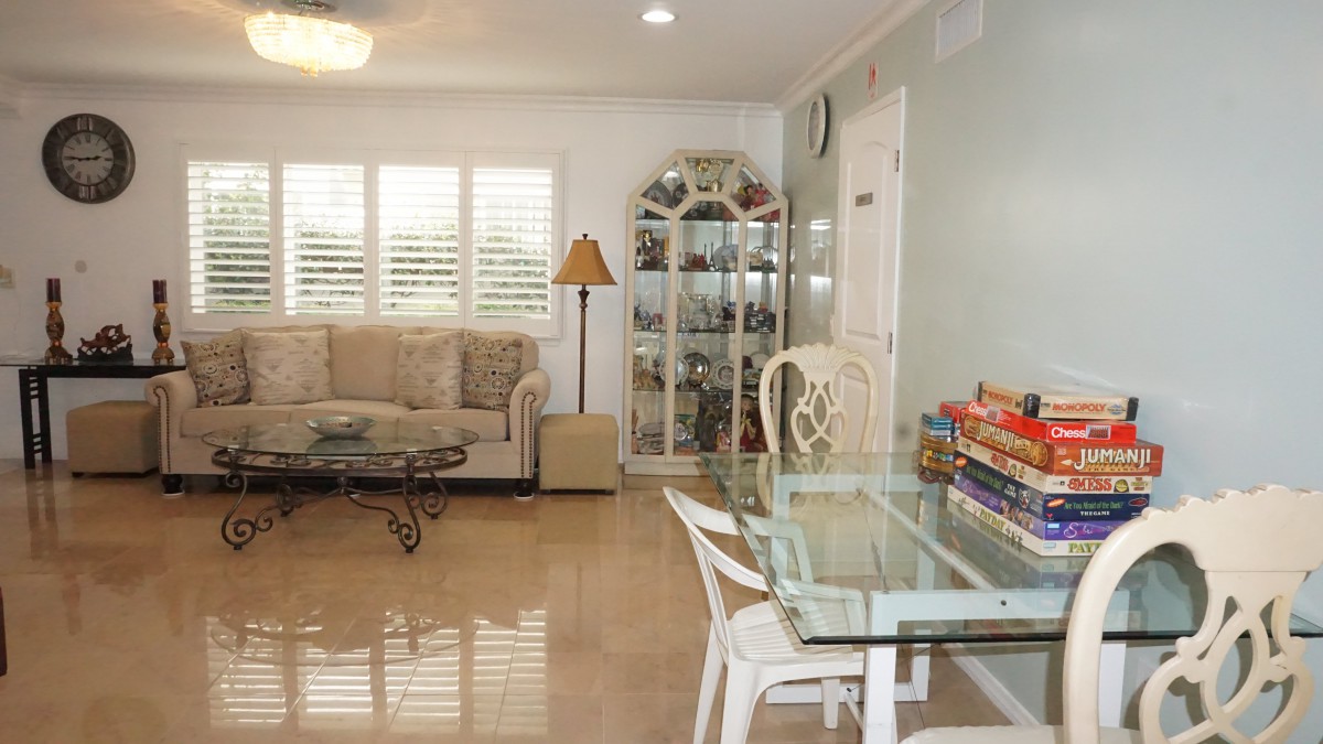 A cozy living room with a glass dining table, a comfy sofa, and decorative shelves.