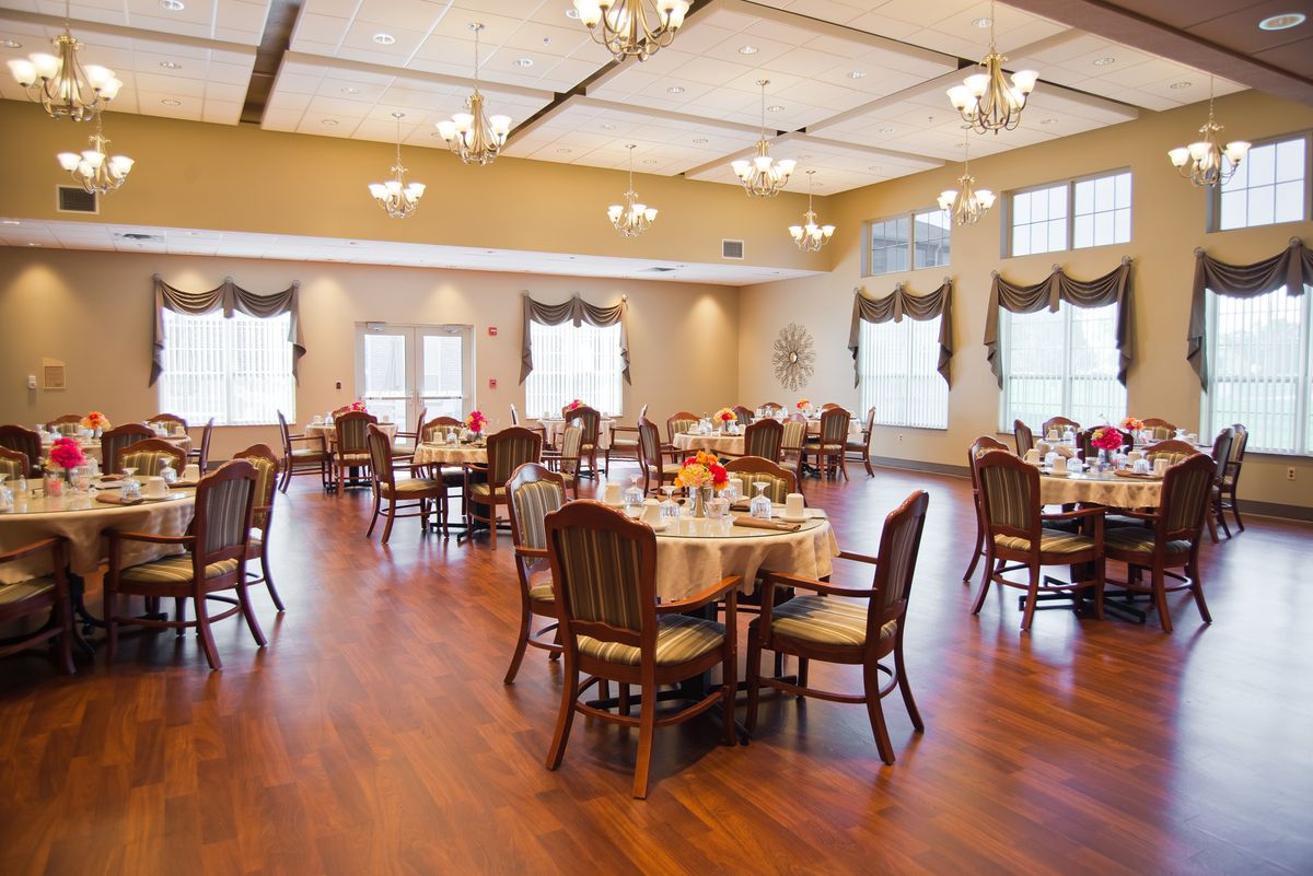 A spacious and elegant dining area with neatly arranged tables and chairs, featuring warm lighting.