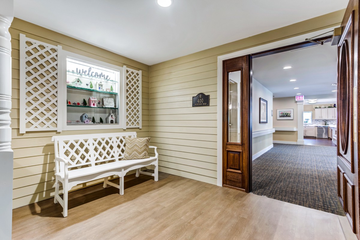 A cozy hallway with a decorative bench and open doorway leading to another room.