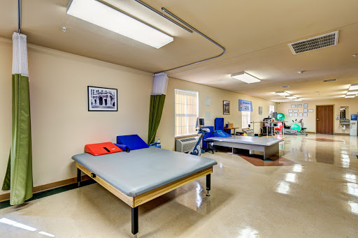 A spacious therapy room equipped with beds and exercise equipment, designed for rehabilitation purposes.