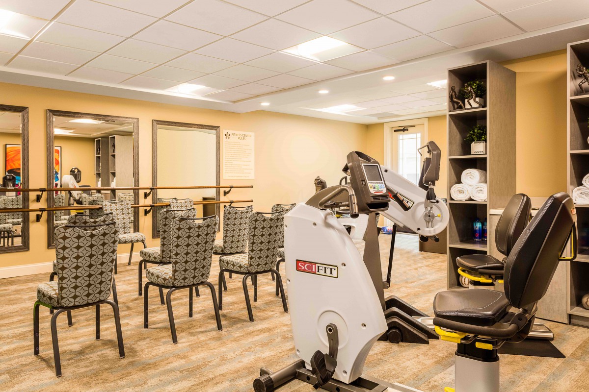 A multi-use room featuring exercise equipment and rows of chairs, suitable for fitness sessions.
