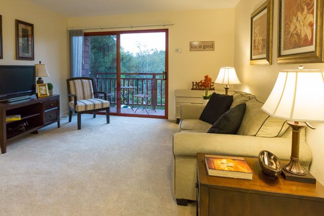 A cozy living room with a comfortable sofa, soft lighting, and a sliding door leading to a balcony.
