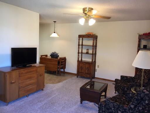 A cozy living room featuring a TV, a wooden cabinet, and comfortable seating.