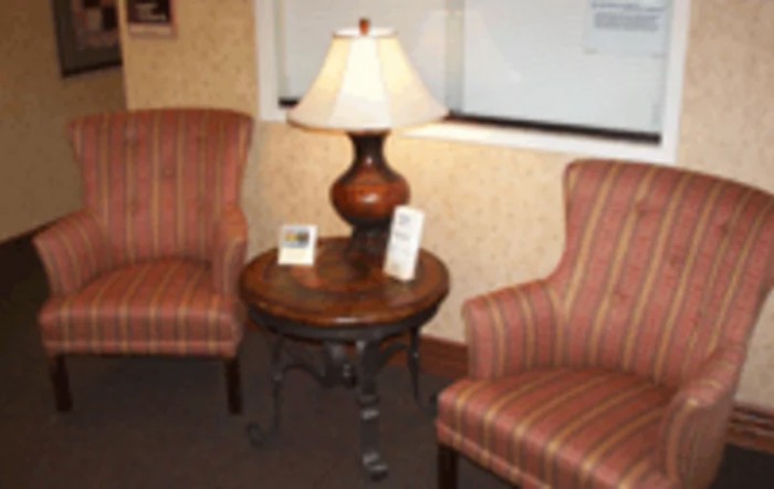 A cozy seating area with two striped chairs and a table topped with a lamp.