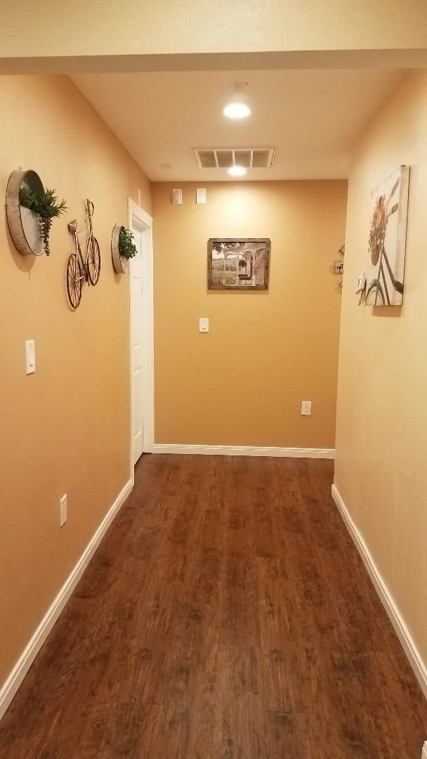 A warmly lit hallway with wooden flooring and decorative items on the walls.