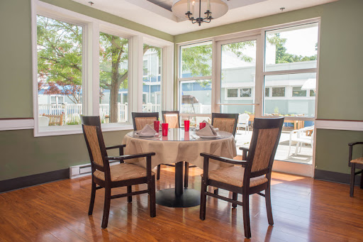 A cozy dining area with a round table set for four, surrounded by windows and natural light.