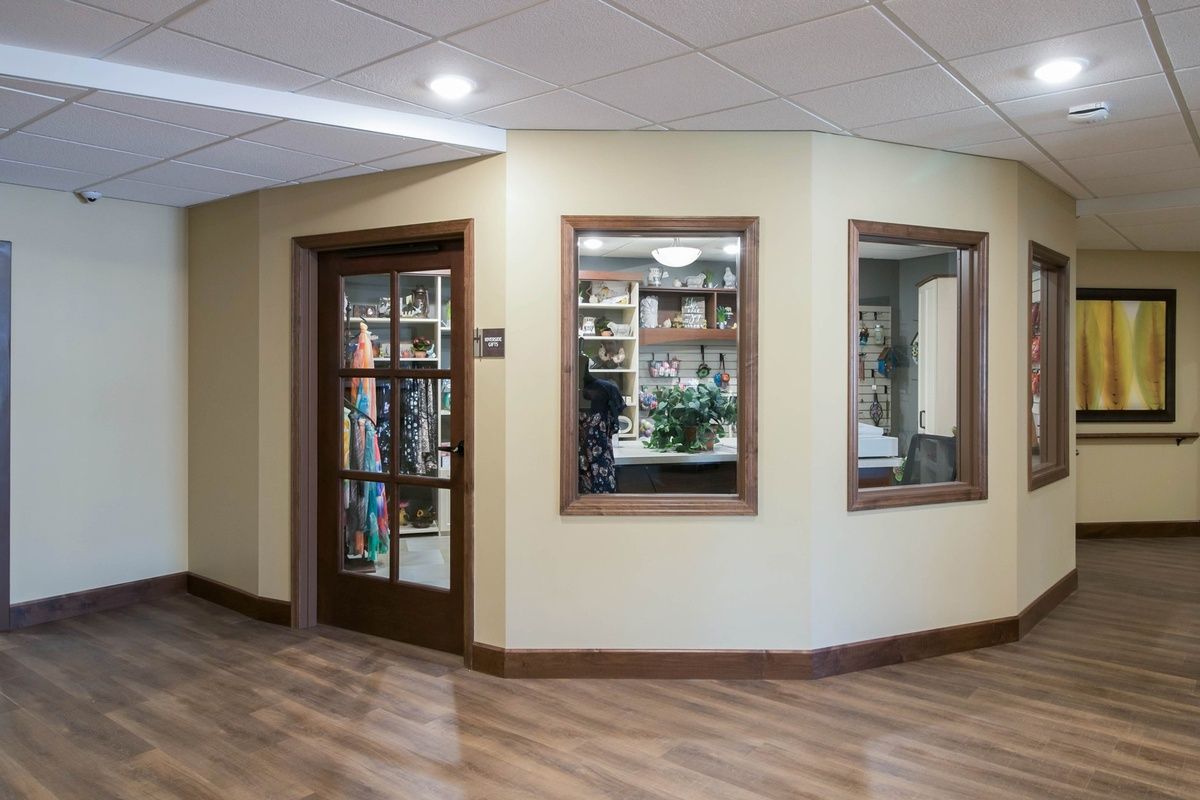 An office interior with wood flooring, featuring a door and windows revealing bookshelves inside.
