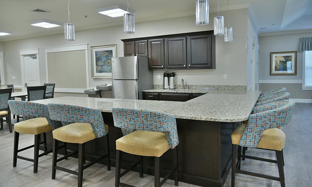 A modern kitchen featuring a spacious countertop with bar stools and sleek appliances.