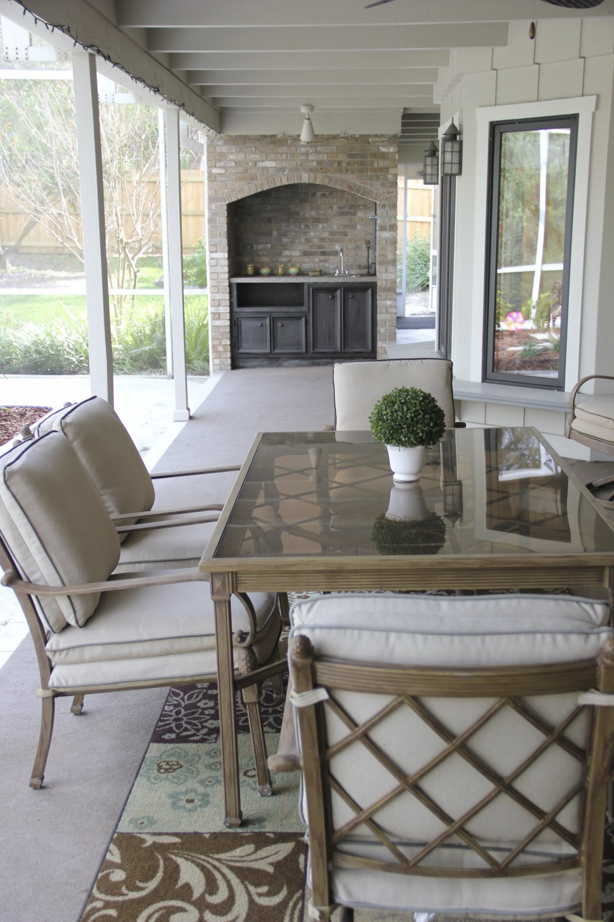 A cozy screened patio with cushioned seating and a glass table, complete with an outdoor fireplace.