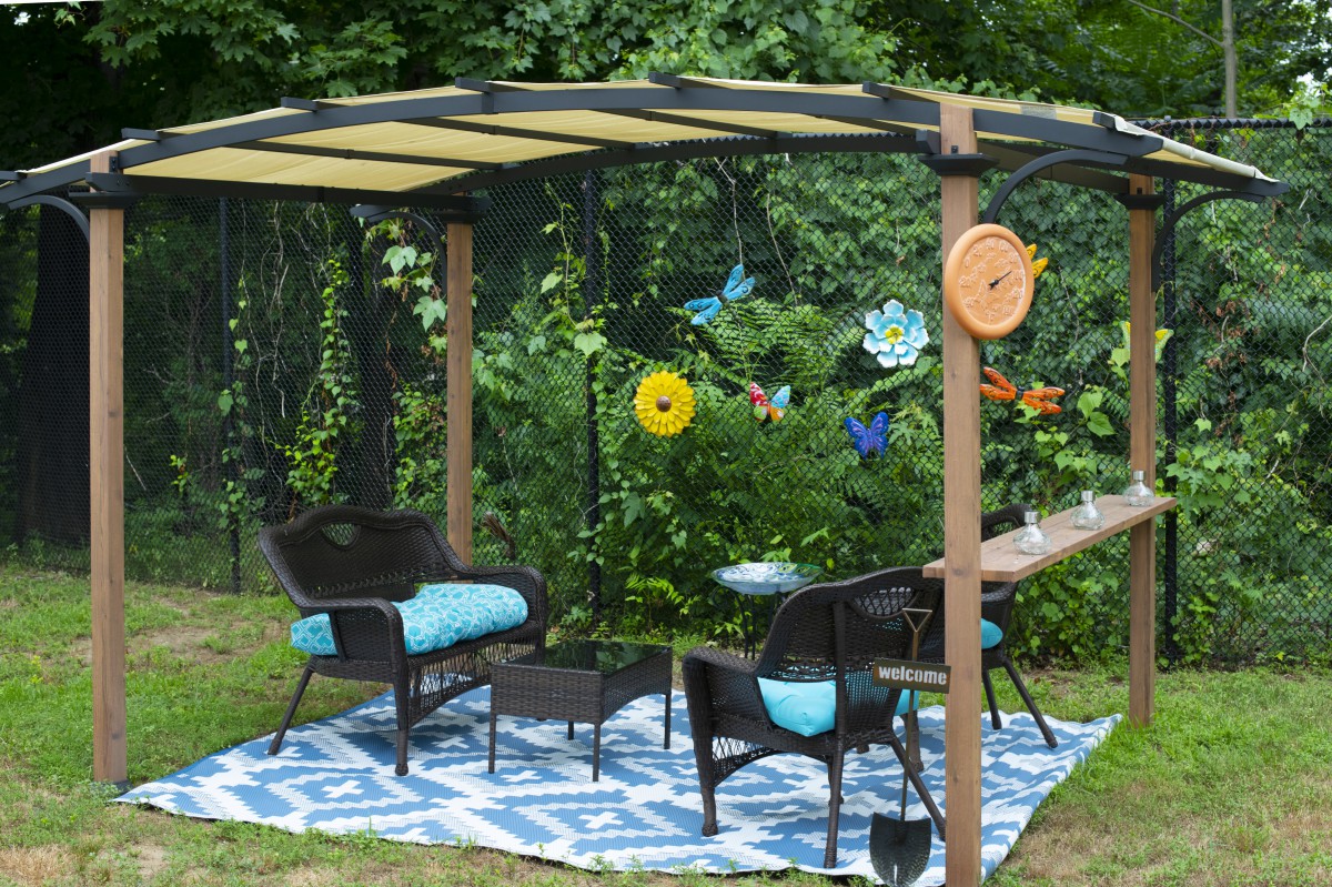 A cozy outdoor patio setup with chairs and a table under a canopy, surrounded by garden decorations.