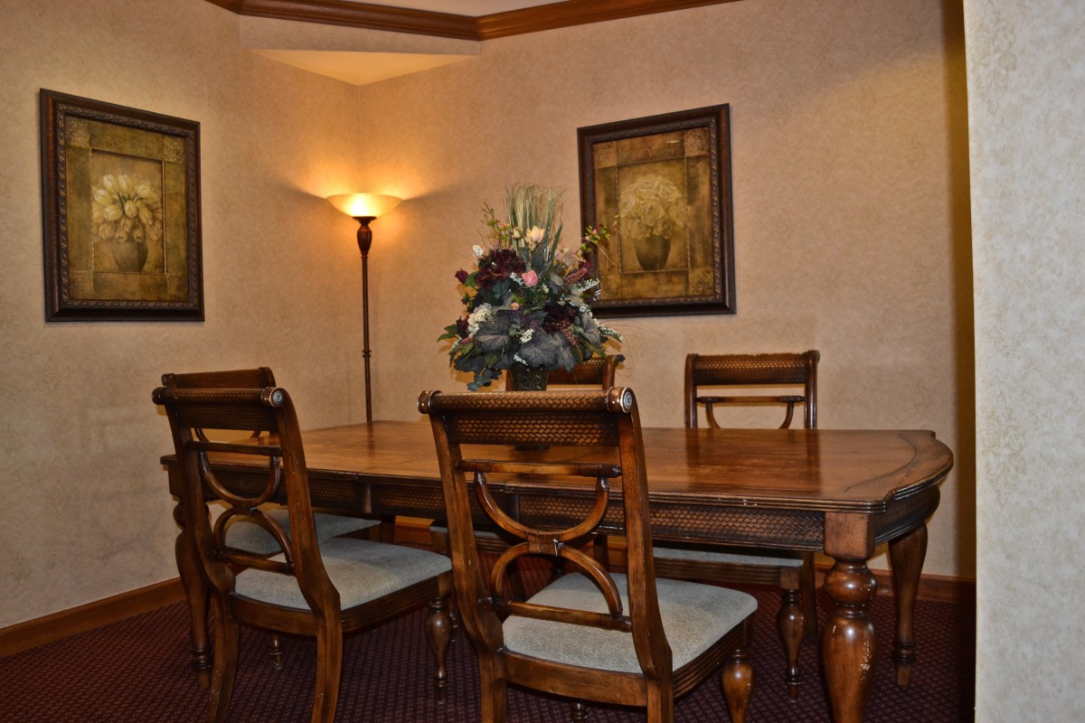 A cozy dining room featuring a wooden table with matching chairs, soft lighting from a floor lamp, and decorative artwork on the walls.