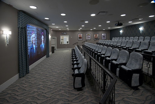 A modern auditorium equipped with comfortable seating and a large projector screen for presentations.