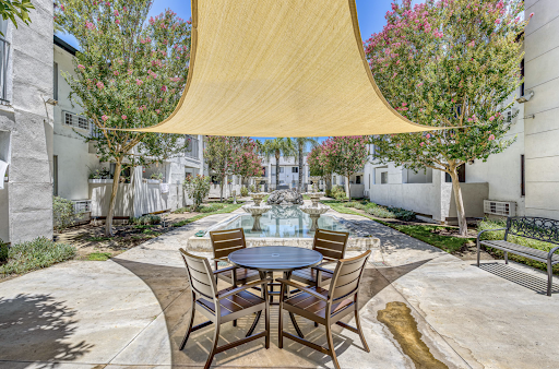 A serene outdoor patio area with a stylish shade sail, offering a perfect spot for relaxation near a beautiful water feature.