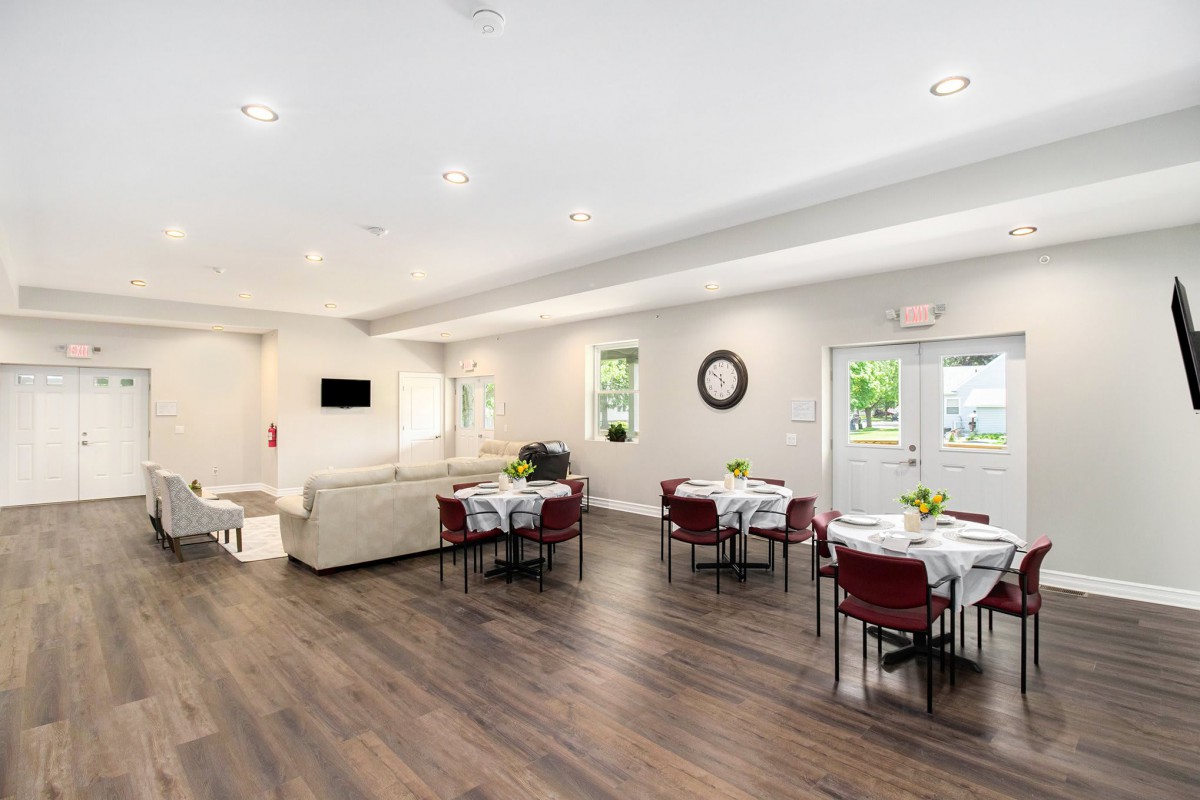 A modern dining area with neatly arranged tables and chairs, illuminated by natural light.