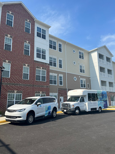 A view of a residential apartment building with parked vehicles outside on a clear day.