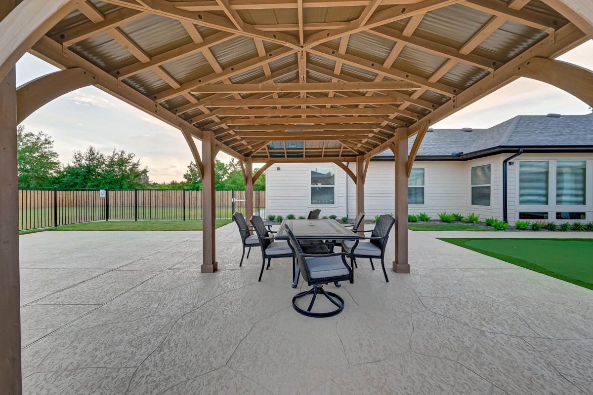 A spacious patio with a wooden pergola and outdoor dining set.