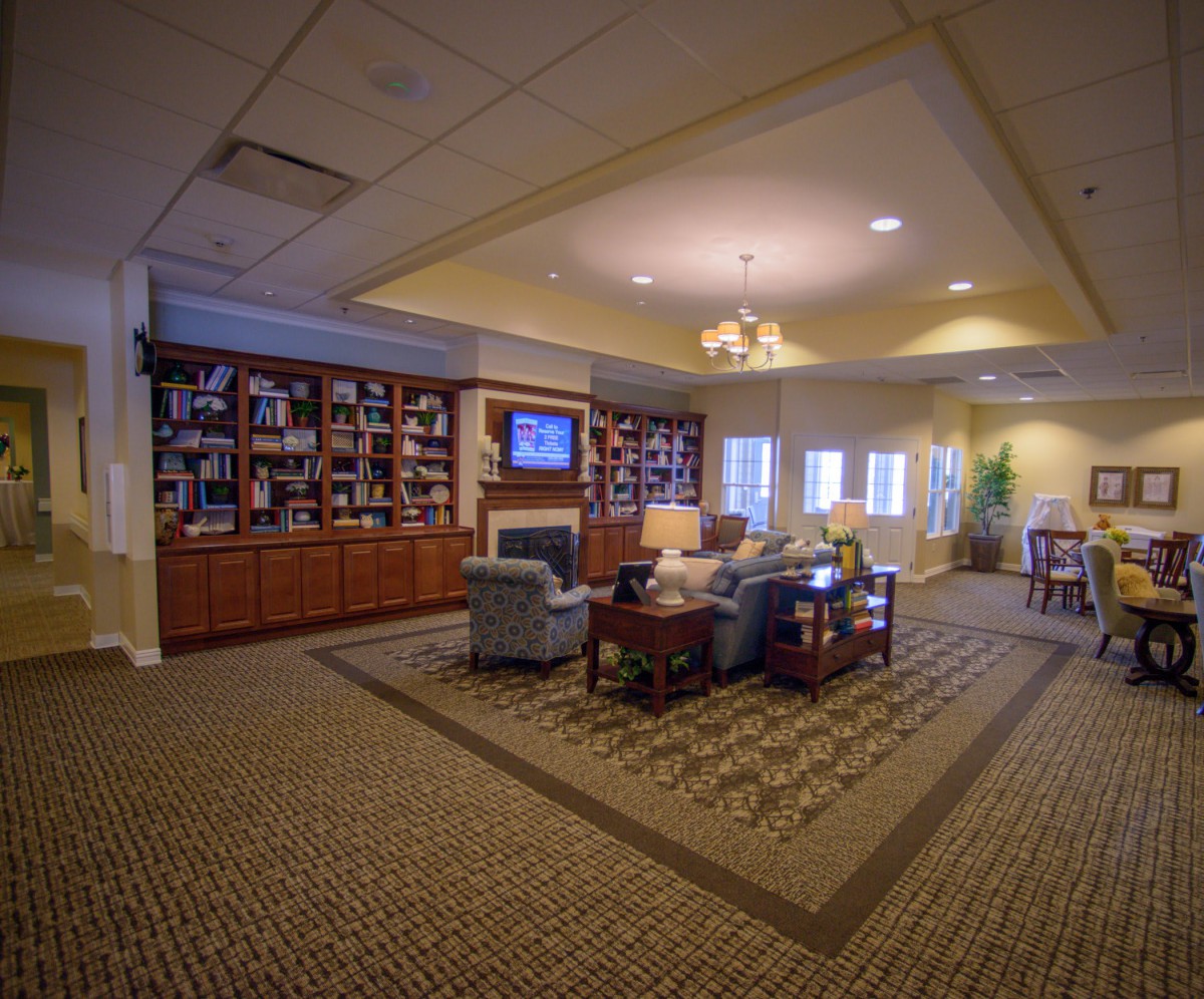 A cozy living room interior with bookshelves, comfortable seating, and a television.