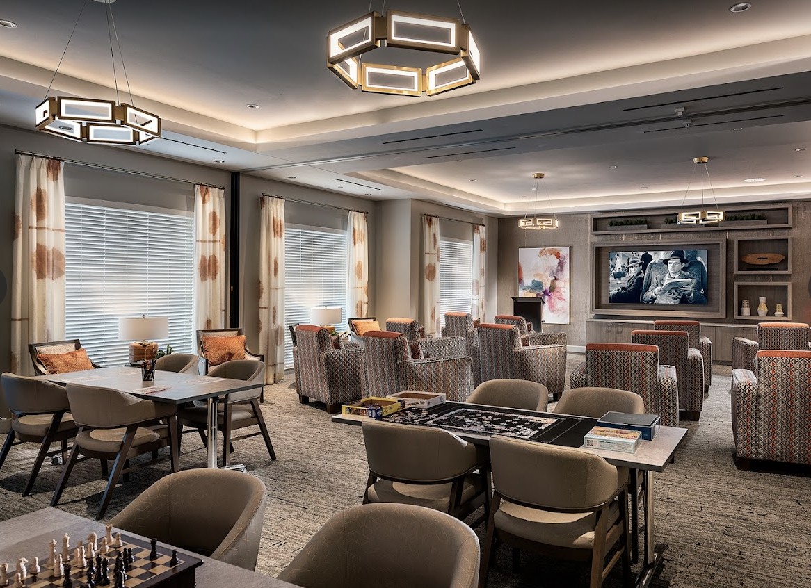 A modern lounge area with comfortable seating and a large television on the wall.