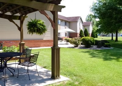 A backyard patio with furniture overlooking a well-maintained lawn and residential building.