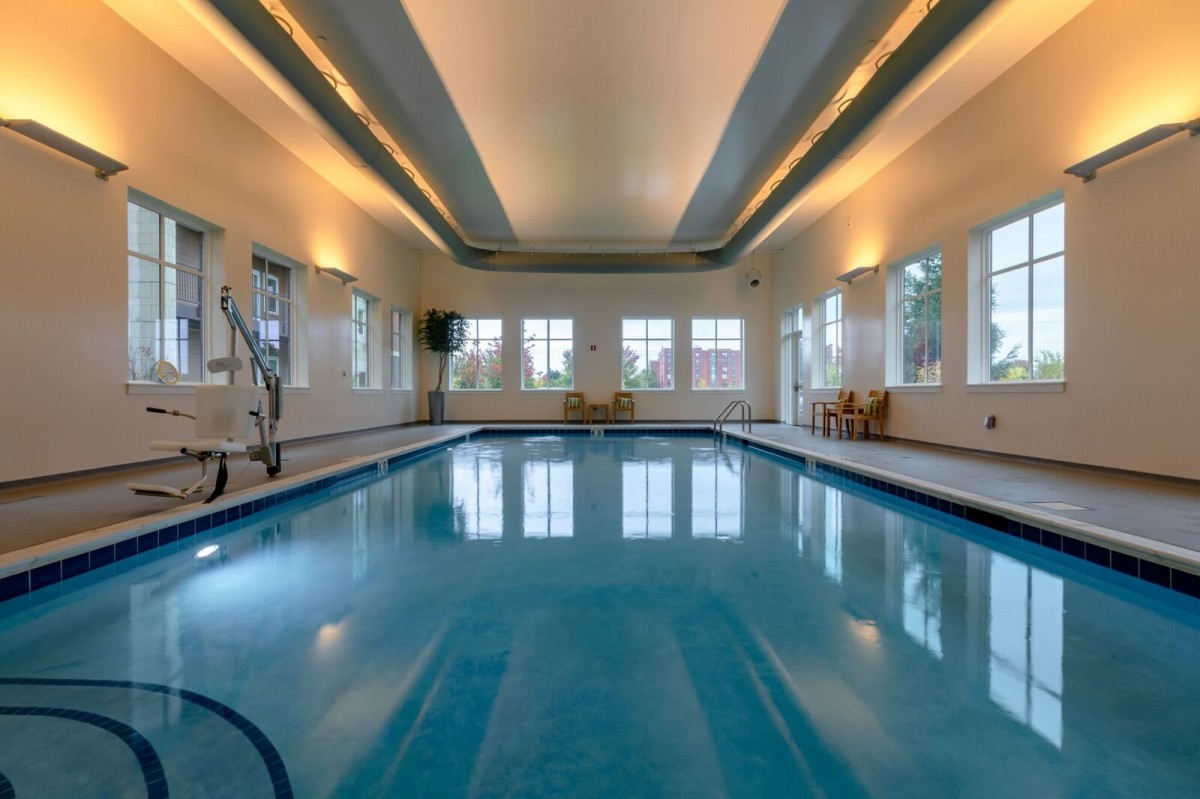A serene indoor swimming pool with elegant lighting and large windows.