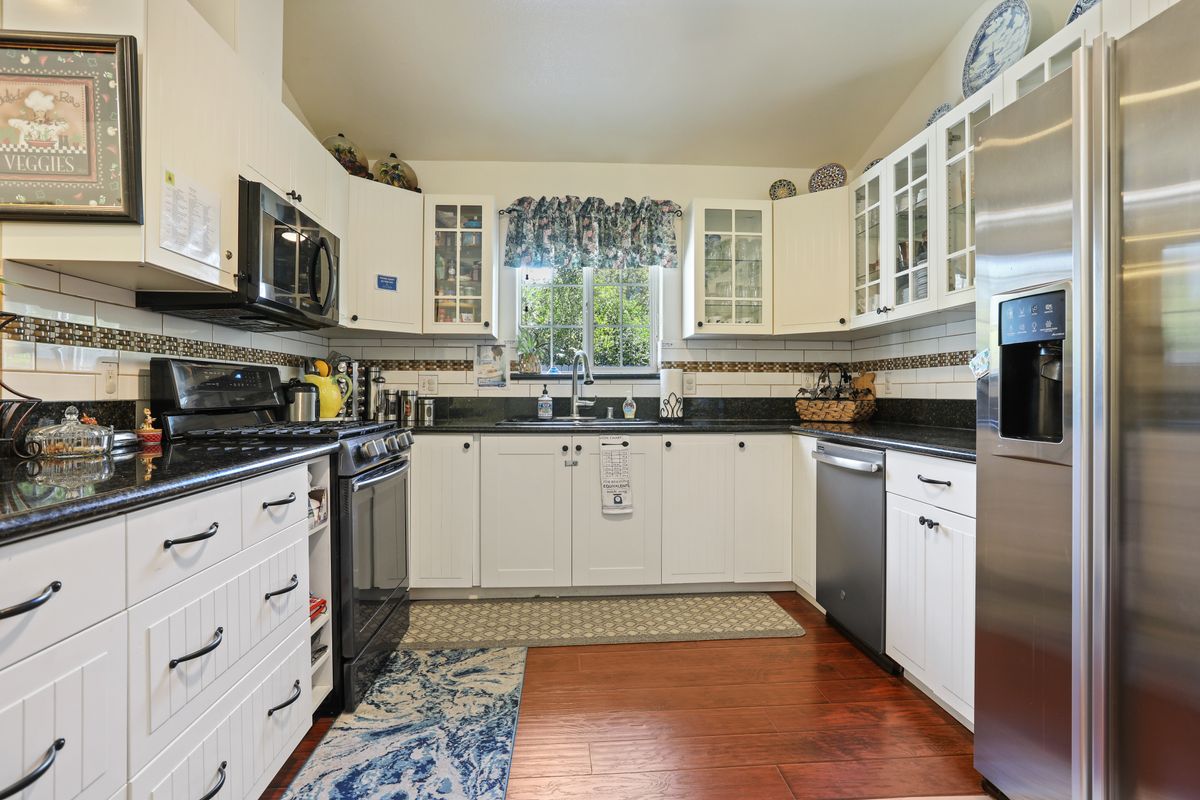 A modern kitchen with white cabinets and dark countertops.