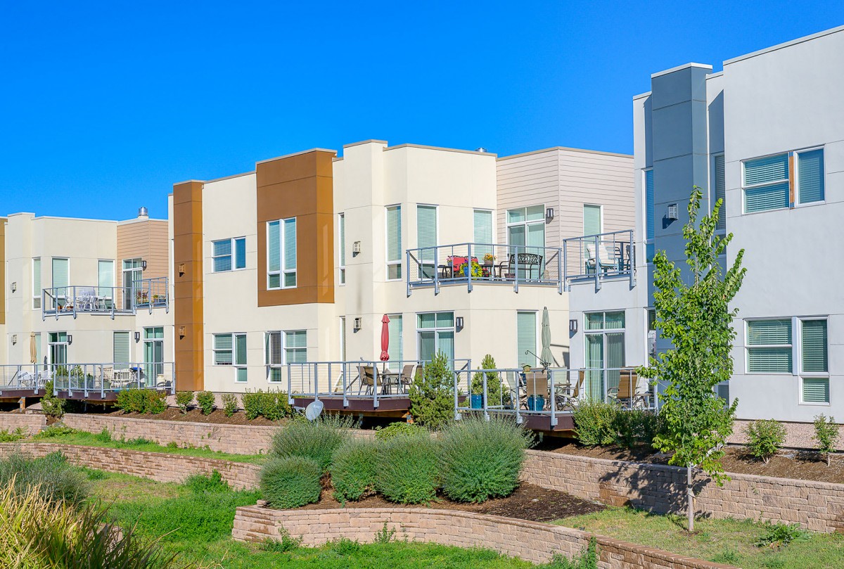 Modern apartment complex with balconies and landscaped surroundings under a clear blue sky.