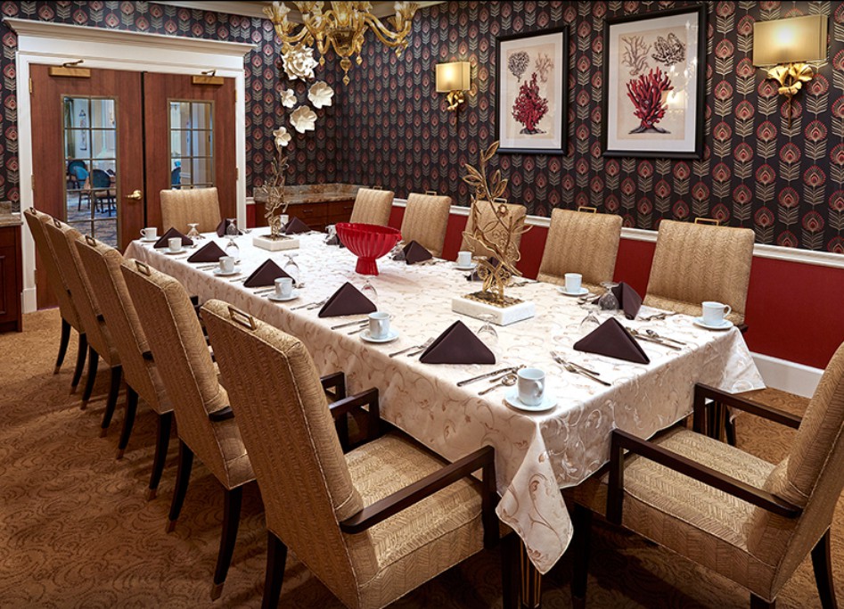 A formally set dining room with elegant decor, featuring a long table adorned with neatly arranged plates, cups, and napkins.