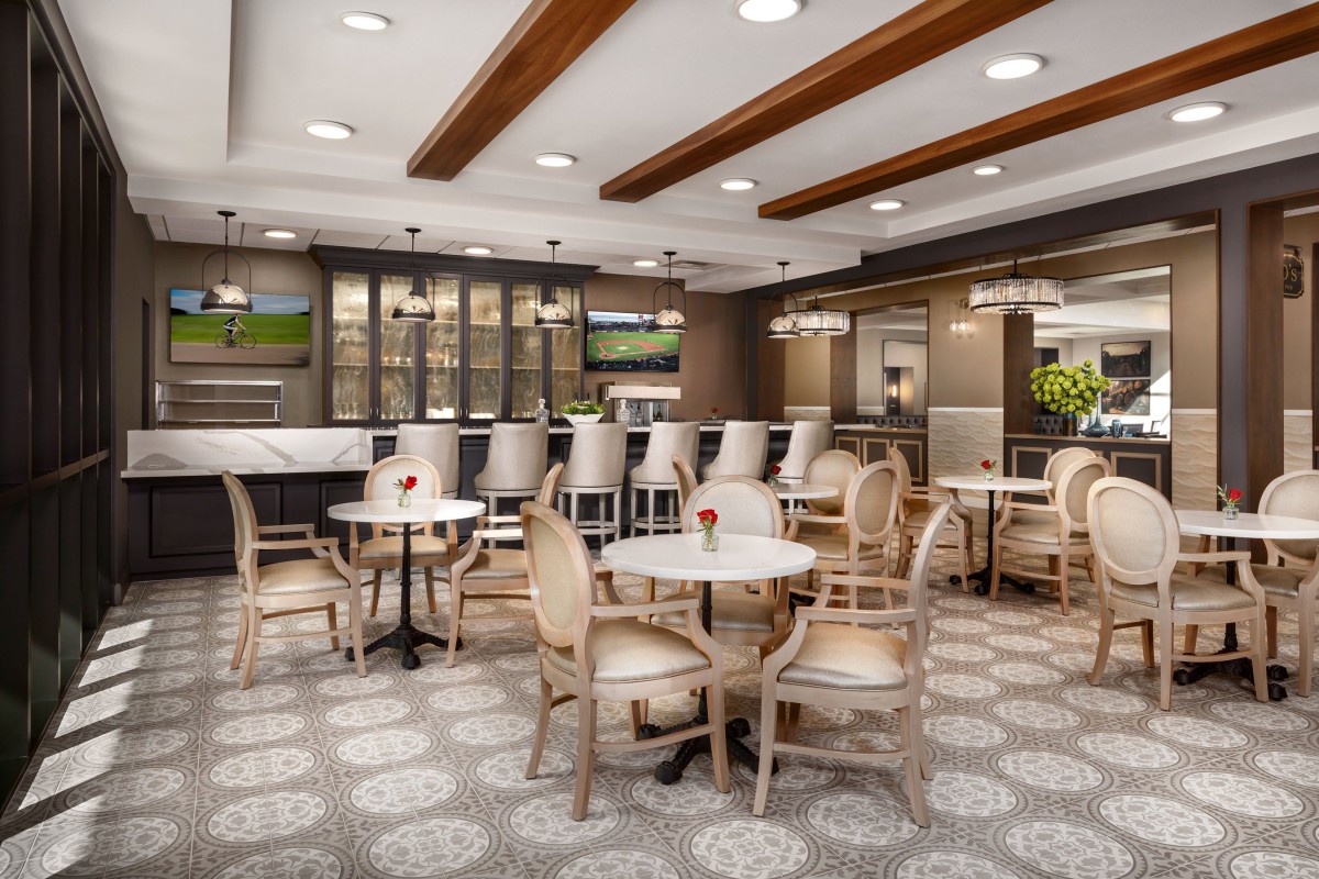 A modern restaurant interior featuring a comfortable dining area with tables, chairs, and bar seating.