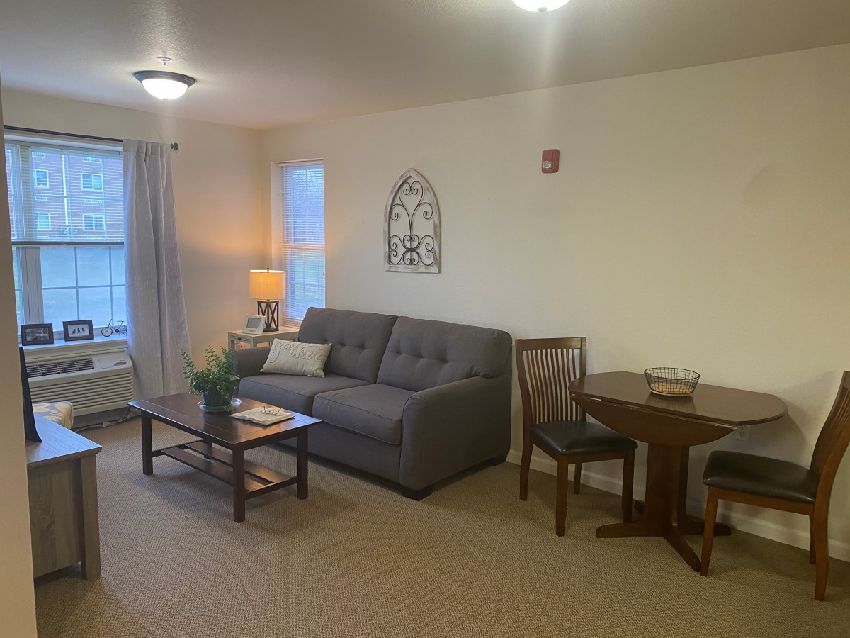 A cozy living room with a sofa, coffee table, and dining area.