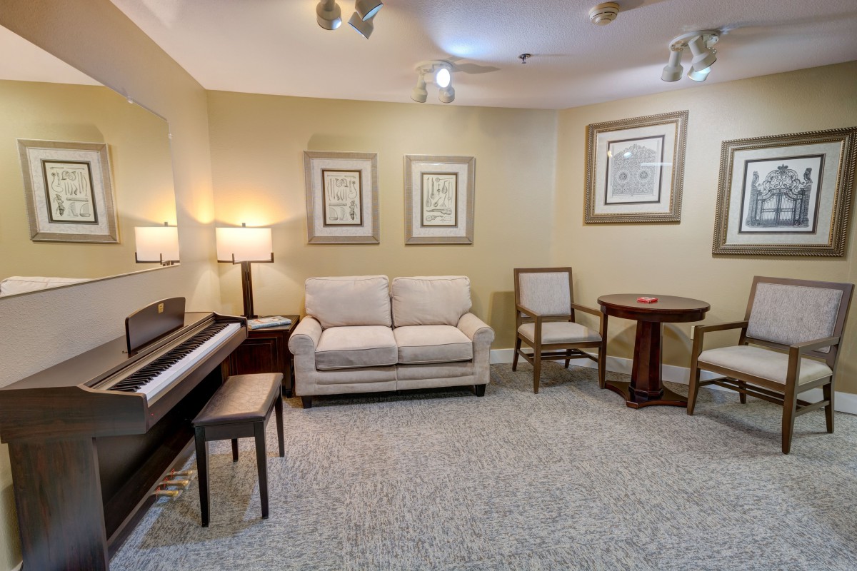 A cozy living room featuring a piano, comfortable seating, and wall art.
