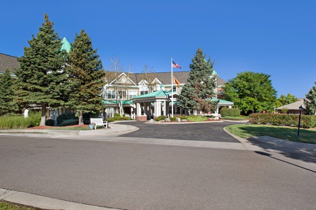 A large building with a green roof surrounded by trees and set against a clear blue sky.