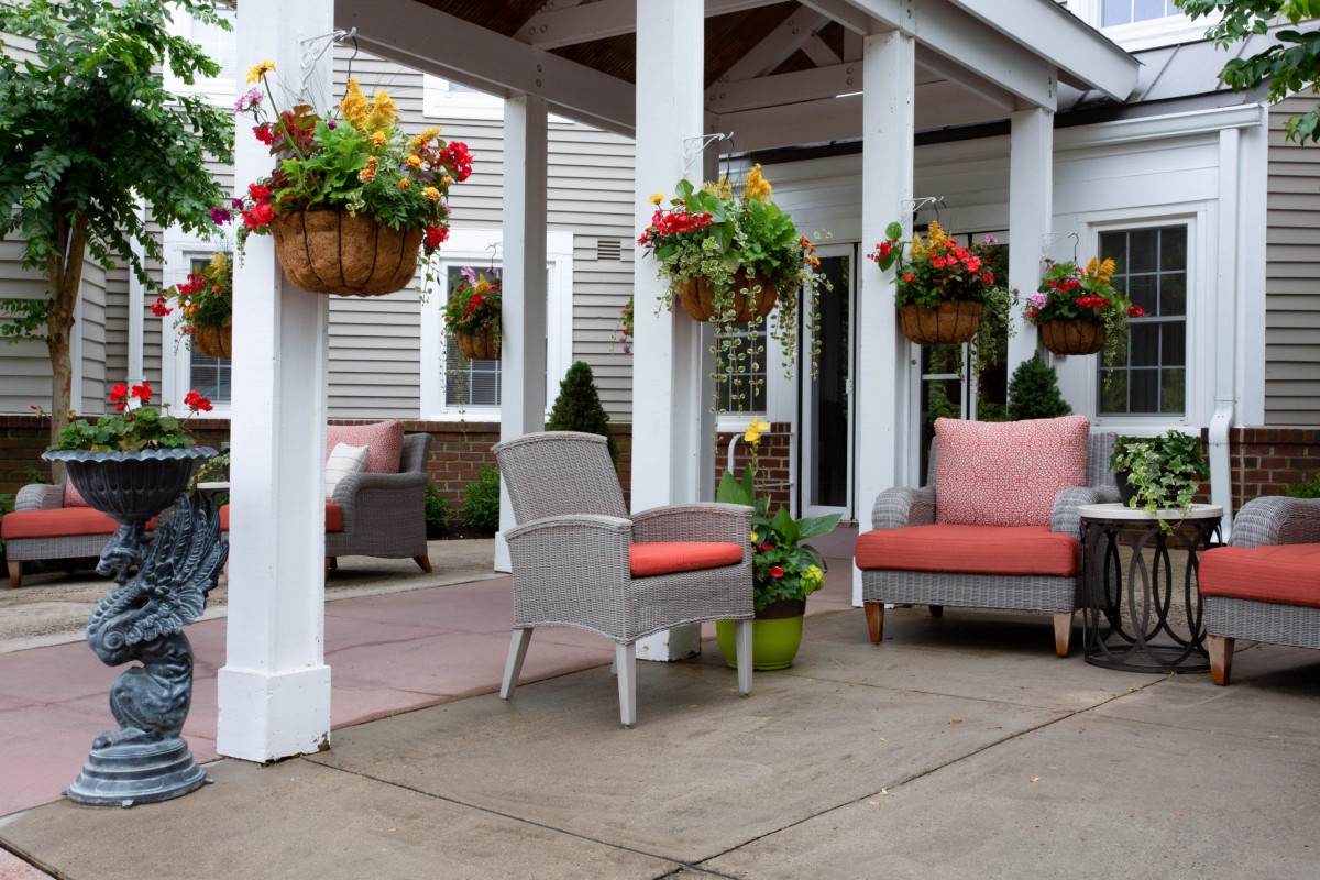 A cozy patio area with comfortable seating and colorful hanging flower baskets.