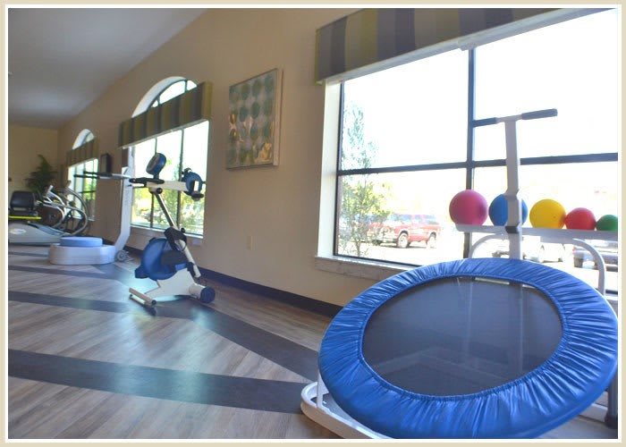 An indoor gym space equipped with a trampoline and other exercise equipment.