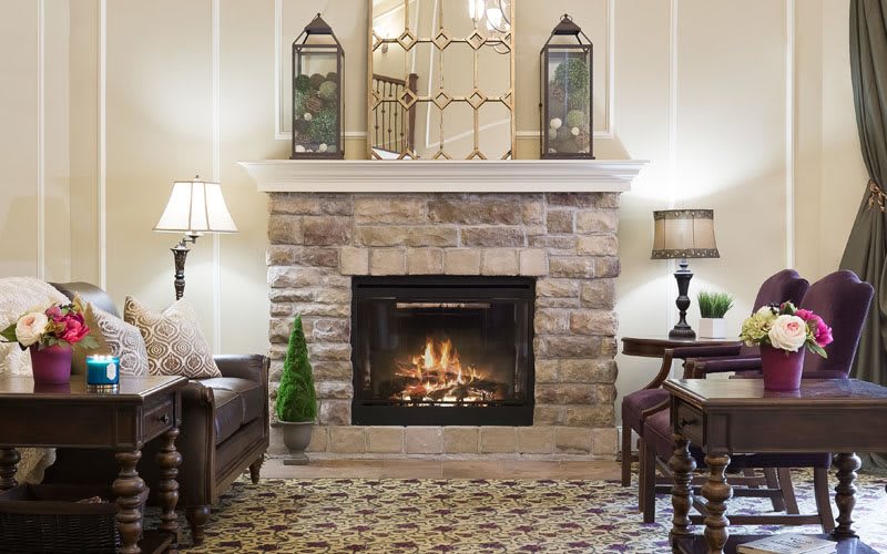 A cozy living room featuring a stone fireplace, elegant lamps, and classic decor.
