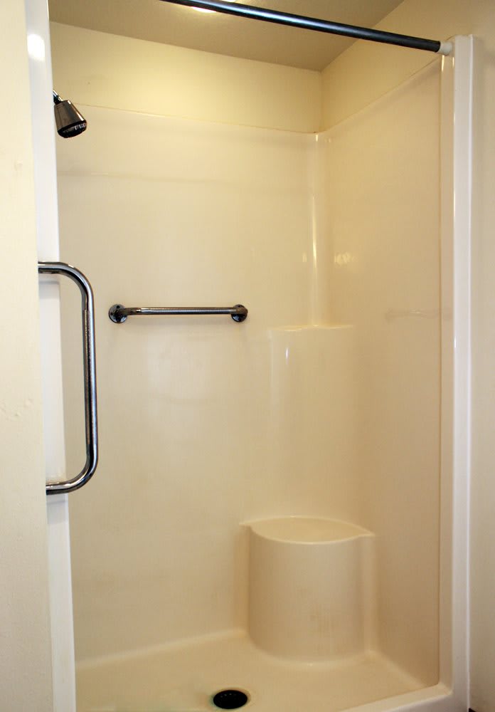 A simple bathroom shower with a towel and grab bar.