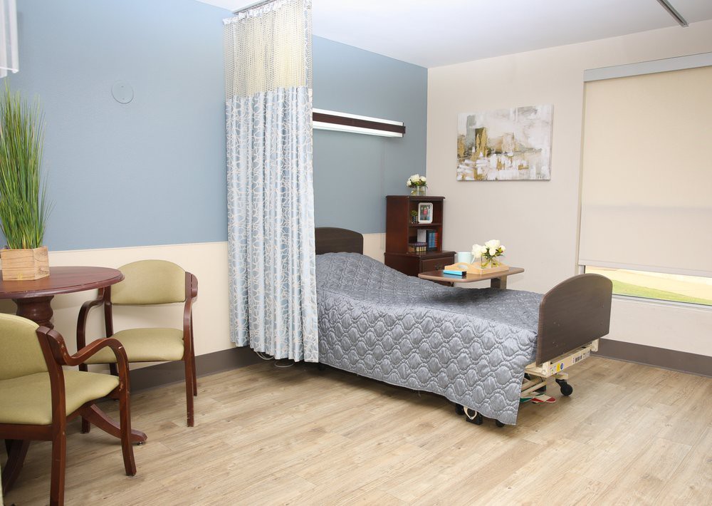 A well-organized hospital room with a patient bed and seating area.