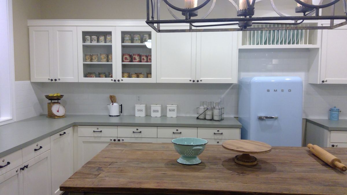 A modern kitchen with white cabinets, a wooden countertop, and organized decor.