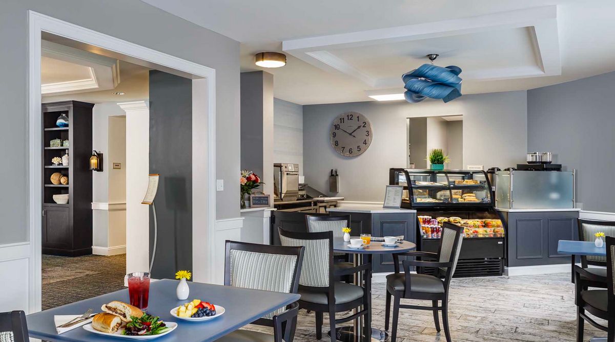 A cozy caf interior featuring tables and chairs, a snack bar, and modern decor.