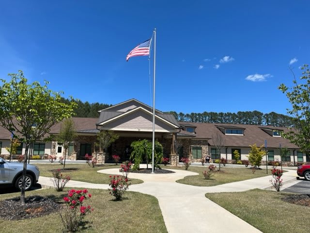 A building with a flagpole on a sunny day, surrounded by landscaped paths and plants.