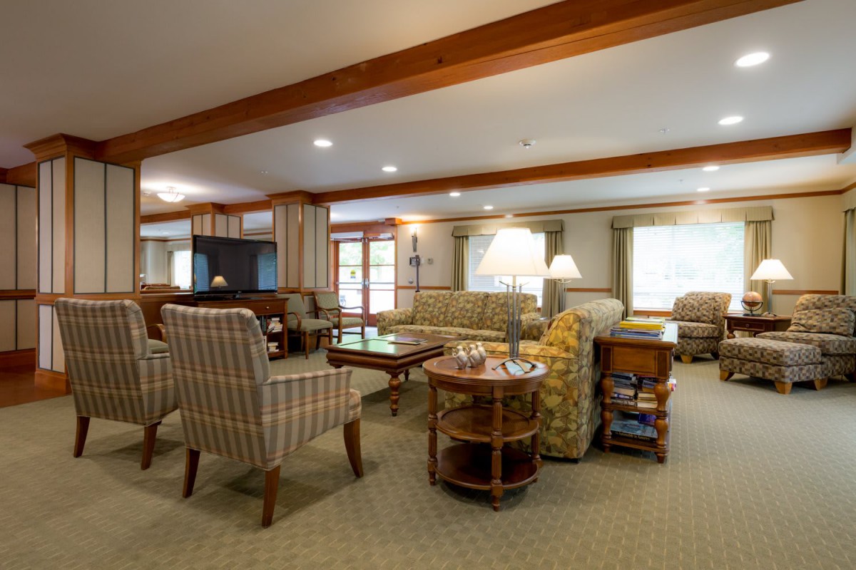 A cozy living room with comfortable seating, wooden beams, and ample lighting.