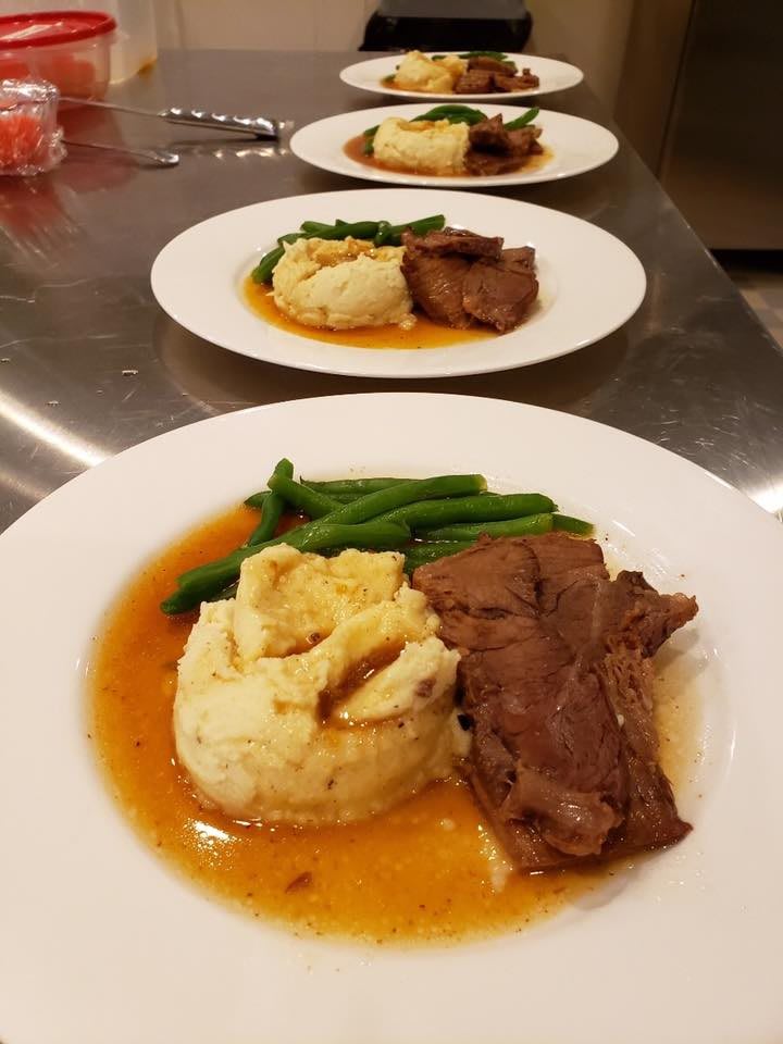 A delicious plated dinner featuring beef, mashed potatoes, green beans, and sauce.