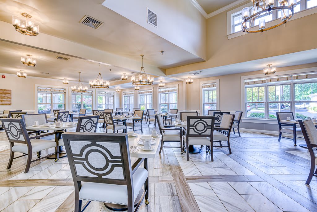A bright and elegant dining room with tables, chairs, and chandeliers.