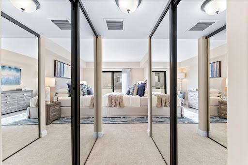 A spacious and elegantly designed bedroom with mirrored closet doors, featuring soft lighting and neutral decor.
