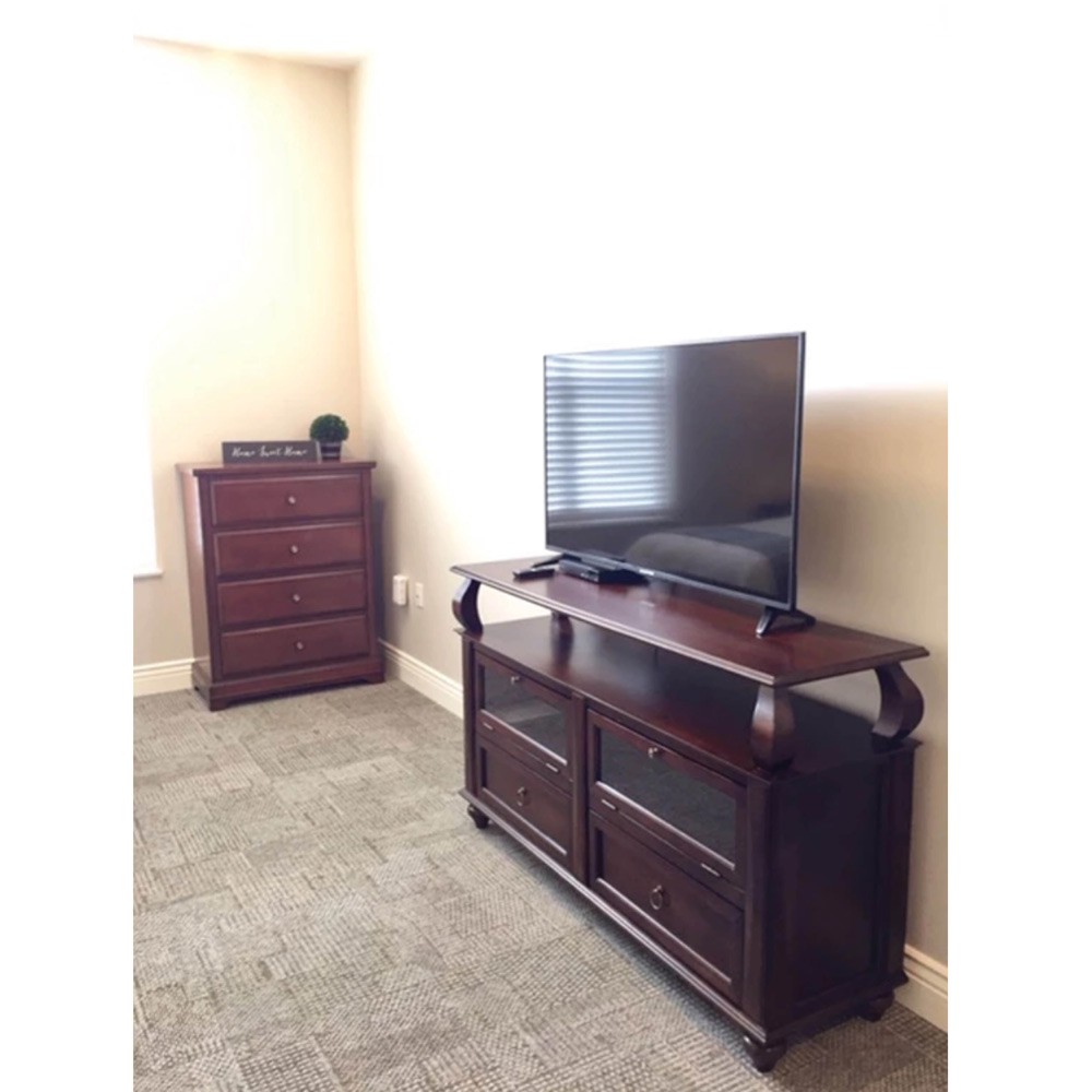 A living room featuring a wooden TV stand and dresser.