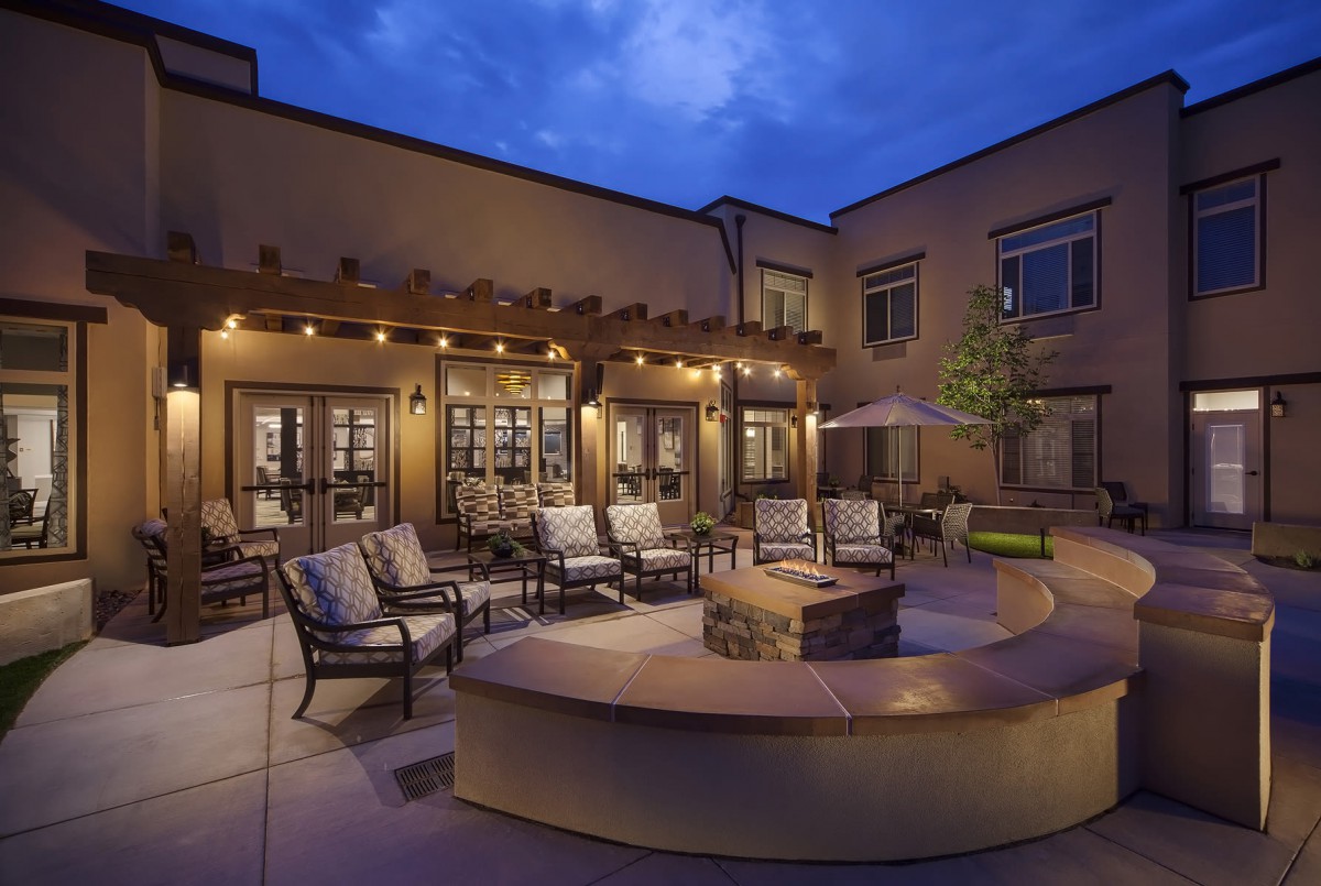 A cozy outdoor patio with a fire pit and comfortable seating, beautifully lit in the evening.