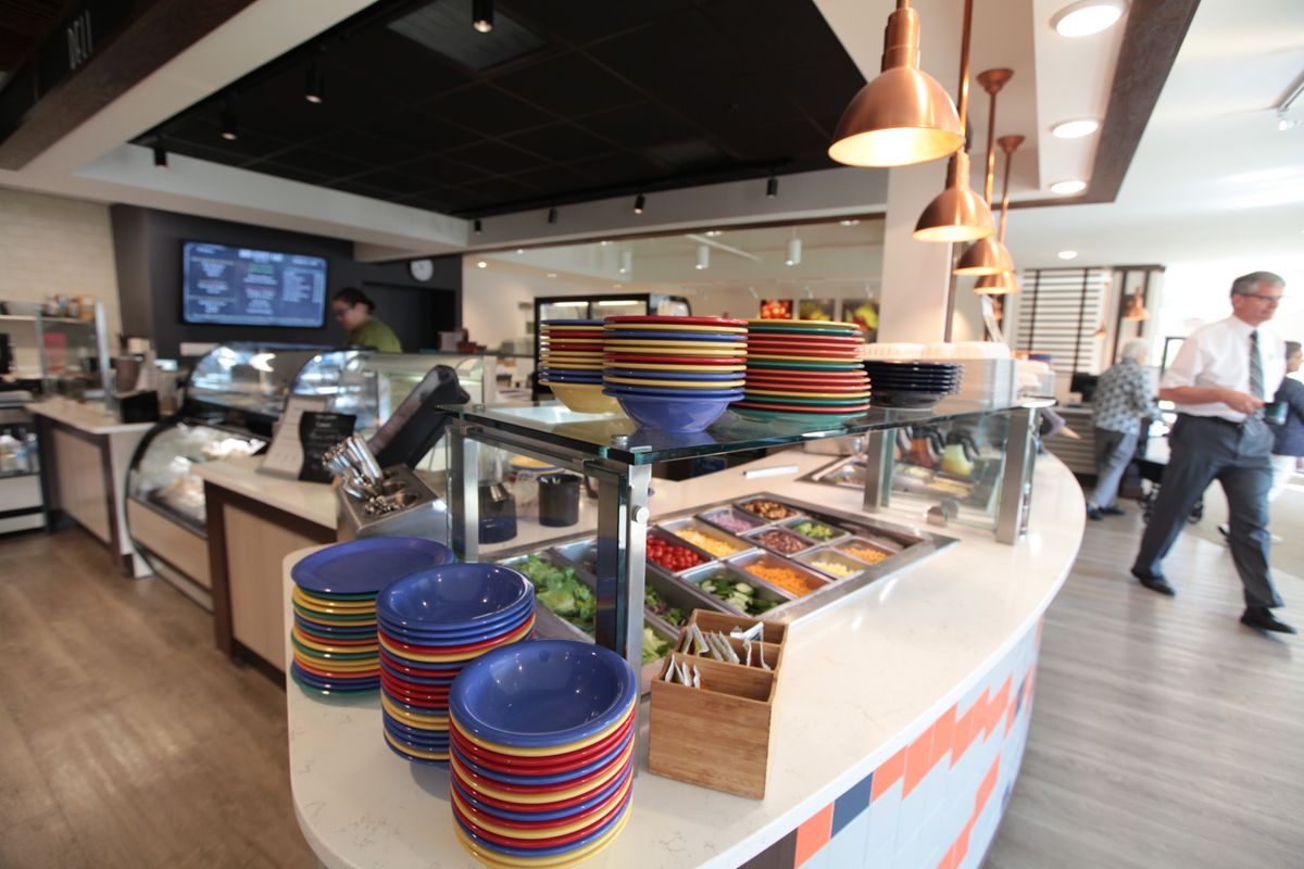 A restaurant interior featuring a counter with stacks of colorful bowls and food preparation area.